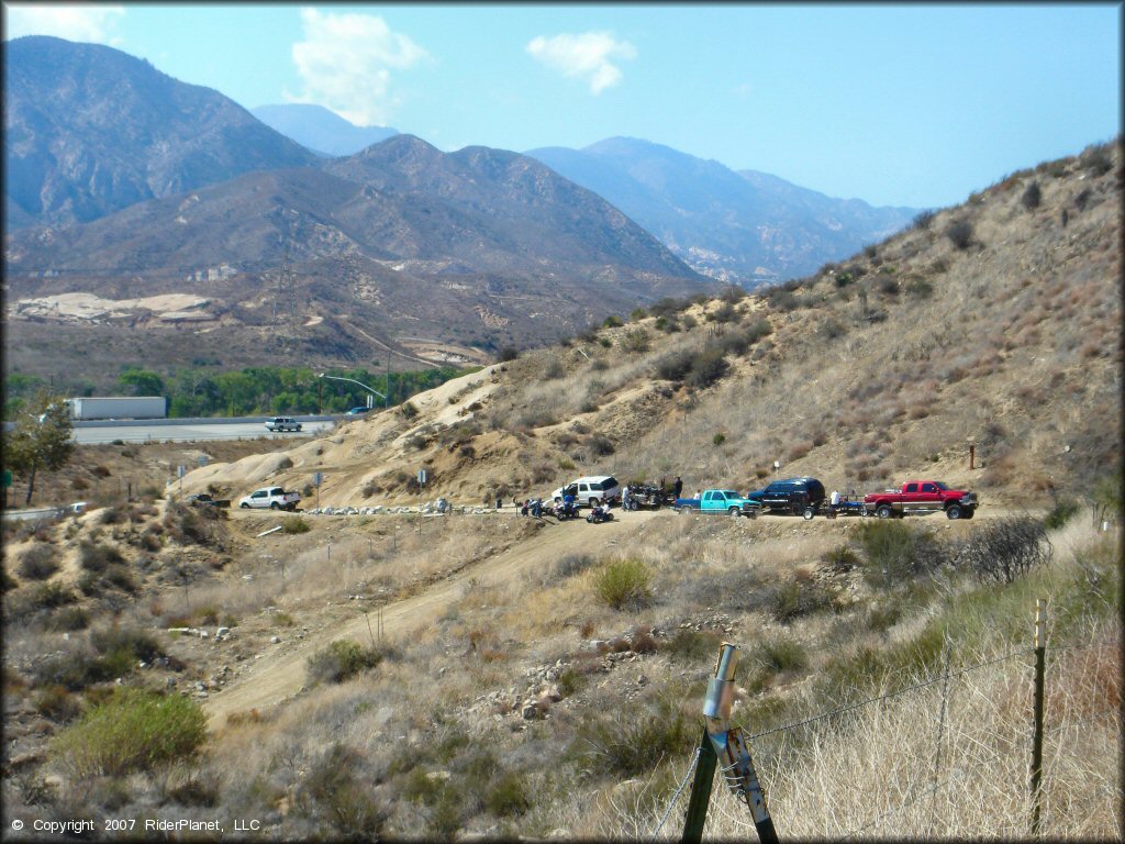 View of staging area with four trucks parked on the shoulder of the road from the trail.