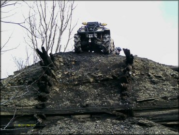 ATV with winch on the front bumper parked on top of dirt mound.