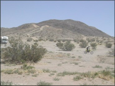 Photo of Class C motorhome parked with Suzuki dirt bike riding through the desert.