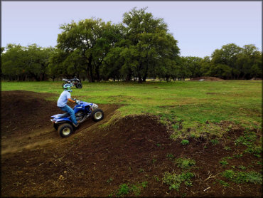 A Yamaha ATV tackles a small hill in the open grassy play area.