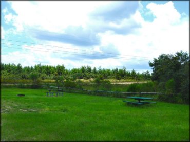 Campsite with picnic table and fire ring surrounded by wooden fencing.