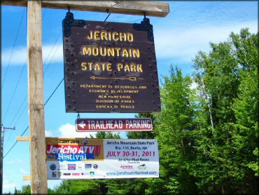 Main entrance sign for trailhead parking with banner promoting annual ATV festival.