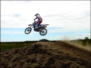 Man taking a jump on blue Yamaha motocross bike.