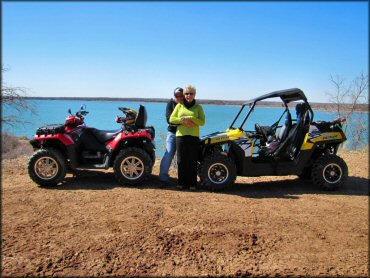 Mature man and woman standing between Polaris Sportsman 850 and Polaris RZR 800.