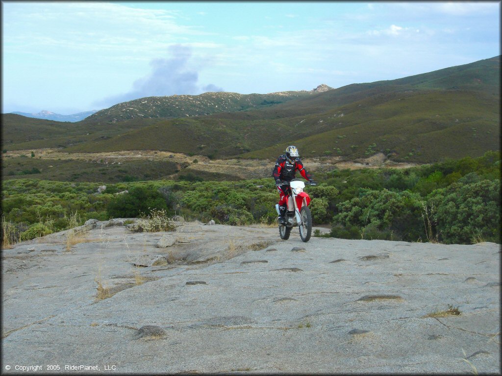 Man on Honda CRF250X riding on solid rock.