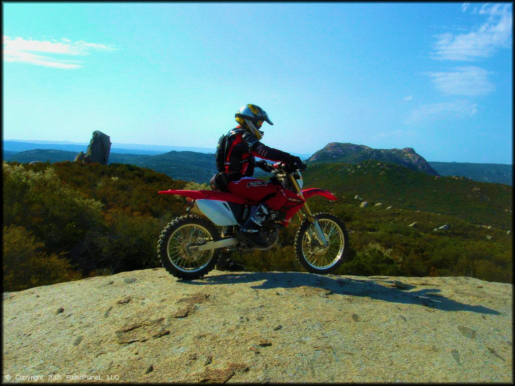 Man on a Honda CRF 250f Motorcycle On Hilltop with a Scenic Background