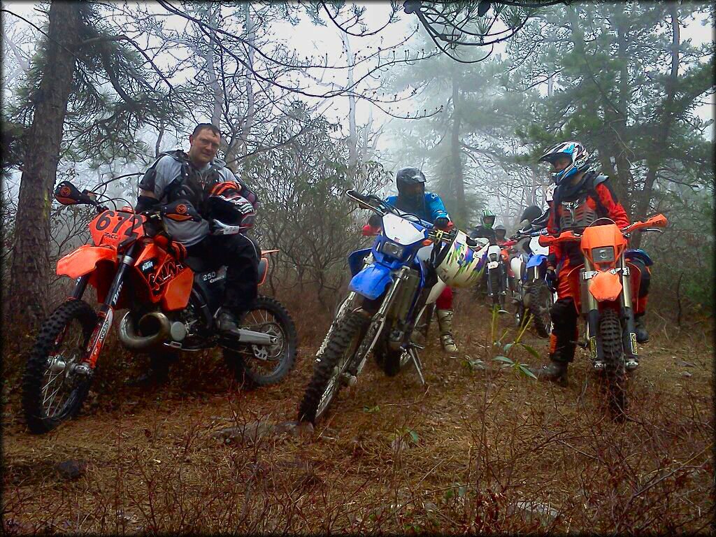 Group of young men sitting on dirt bikes alongside the trail.