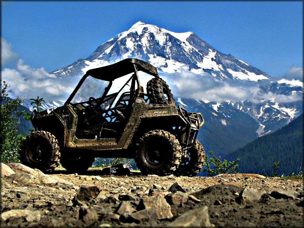 Green UTV parked alongside trail with Mt. Rainier in the background.
