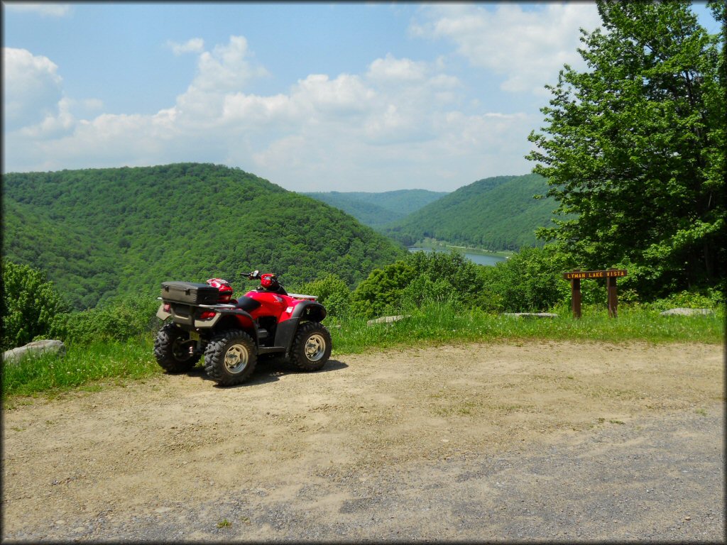 Red Honda ATV parked next to sign for Lyman Lake Vista at Potter County Trail System.