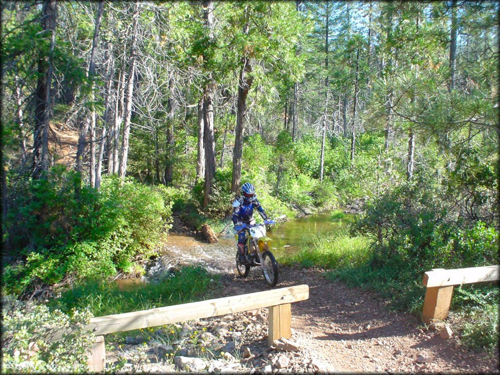 Rider on Suzuki RM150 crossing shallow creek at Foresthill OHV.