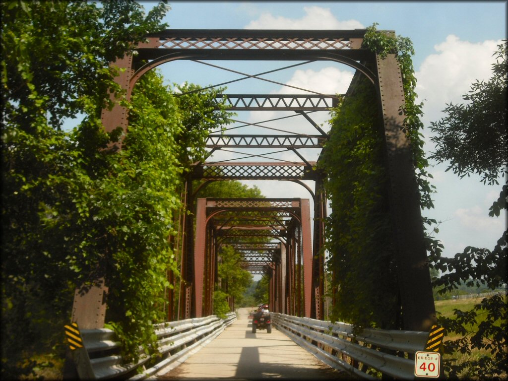 ATV riding down old railroad bridge covered in trees and bushes on the Cheese Country Trail.