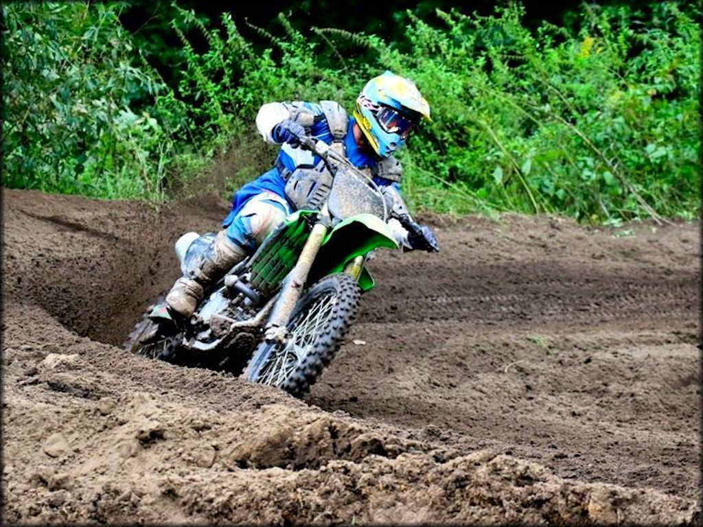 Motocross rider on Kawasaki four stroke dirt bike railing a berm at Leisure Time MX.