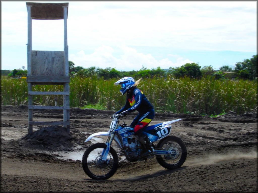 Woman wearing 100% dirt bike goggles and Troy Lee Designs motocross gear on Yamaha dirt bike.