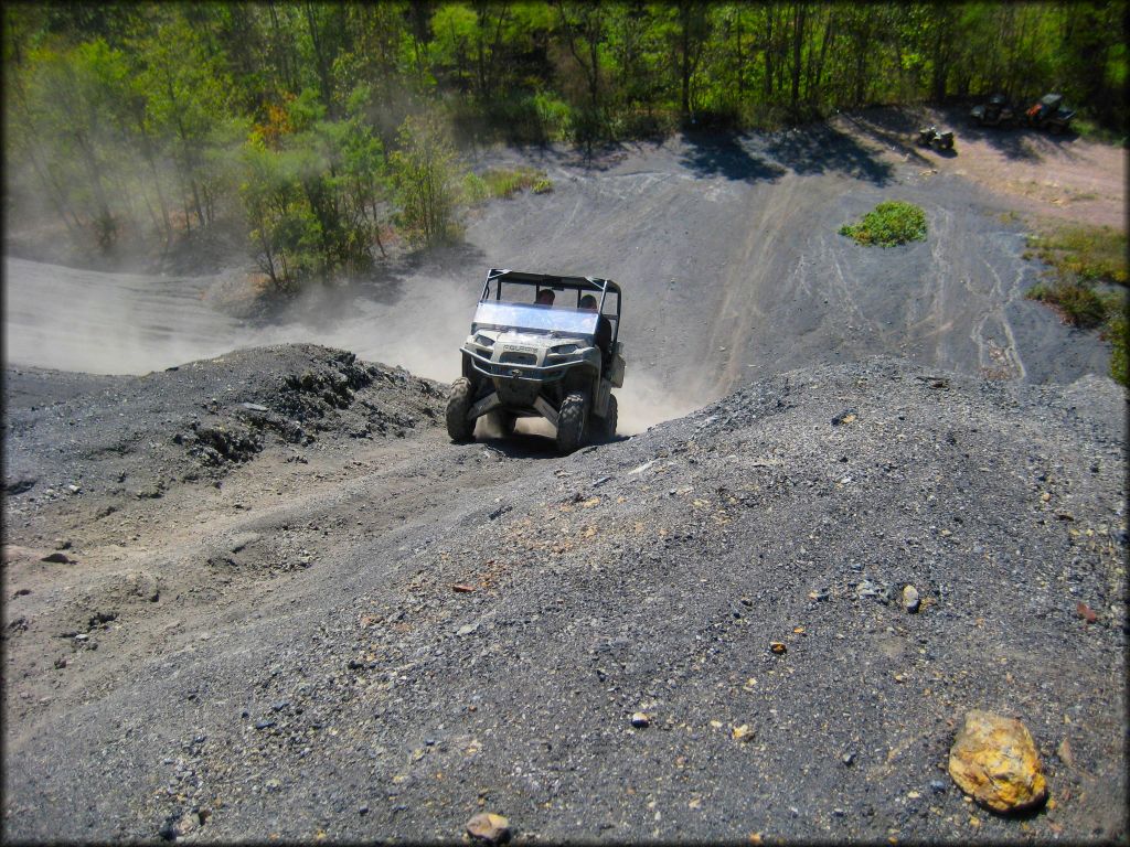 Polaris UTV with hard top climing up steep gravel pit.