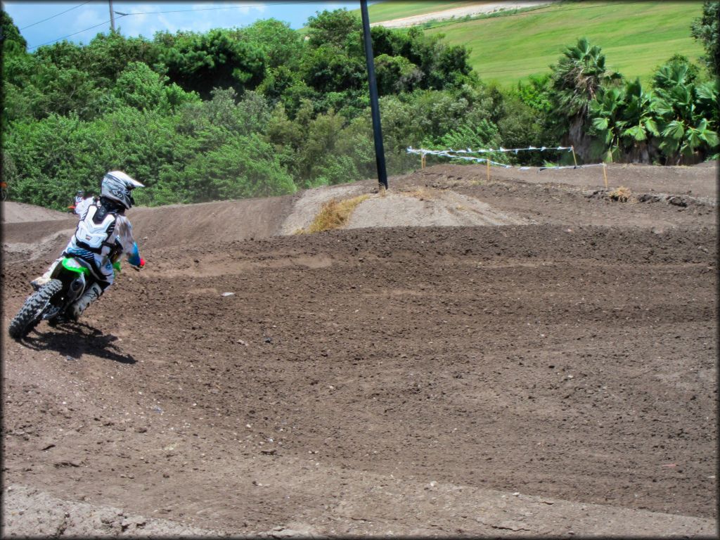 Young man on Kawasaki dirt bike going through berm on motocross track.