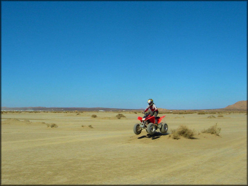 Woman on Honda TRX 250 ATV getting a little air from a small hill.