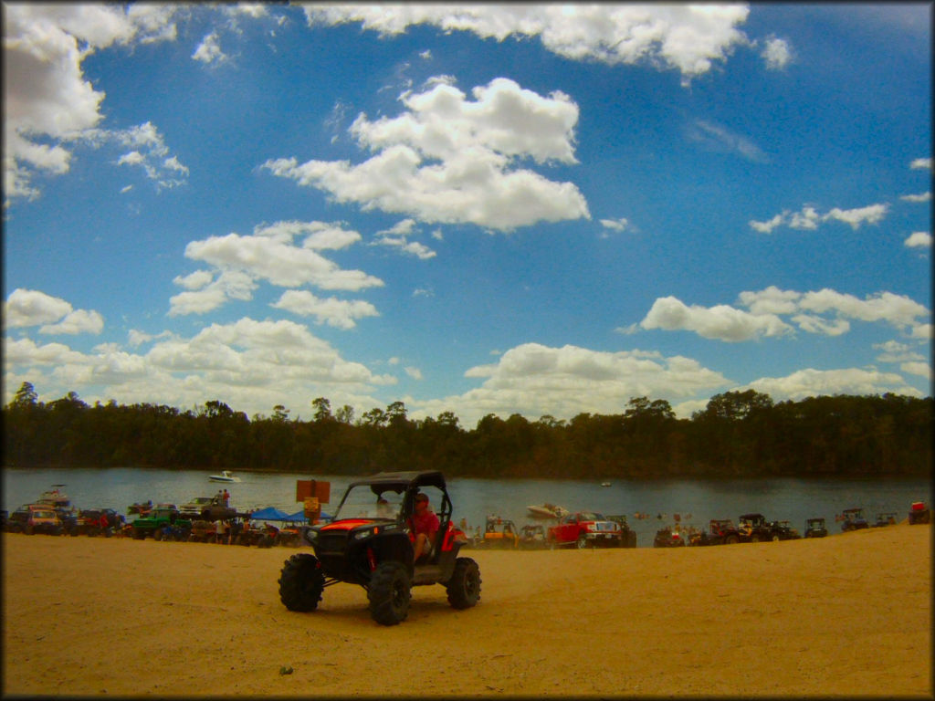 UTV with modified suspension, mud tires and hard top roof driving near beach.