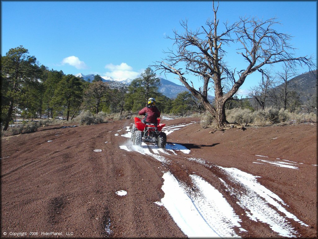Honda TRX 250EX navigating through a patch of snow on ATV trail.