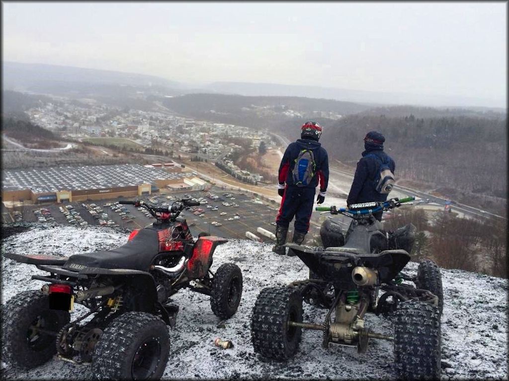 Two Yamaha ATVs parked alongside each other on top of hill.