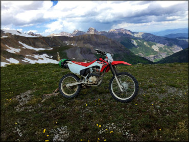 A Honda CRF 230 with scenic mountain and canyon views in the background.