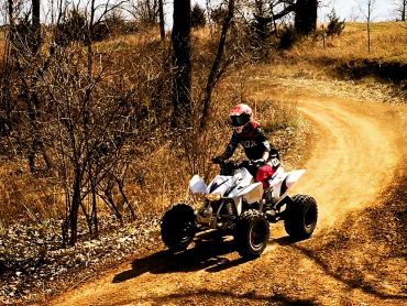 Young woman riding ATV around beginner motocross track.