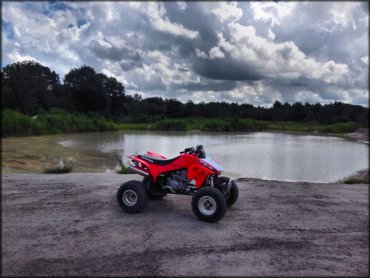 Honda TRX four wheeler parked with small pond in the background.