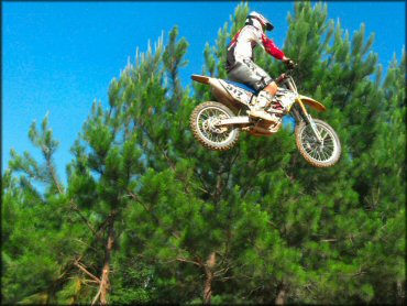 A rider wearing motocross gear and boots on dirt bike catching some big air.