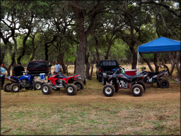 Some visitors relax and enjoy some drinks under the trees after an ATV ride.