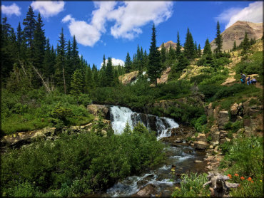 A scenic view of a waterfall on a rocky mountain spring which can be seen from the trail.