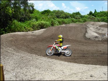 Man on Honda motocross bike going through berm.