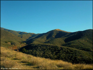 Scenic photo of rolling hills covered with scrub brush and dry grass.