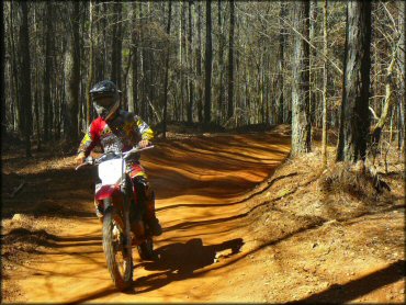 Young man wearing Rockstar motocross gear riding Honda dirt bike navigating smooth ATV trail in the woods.