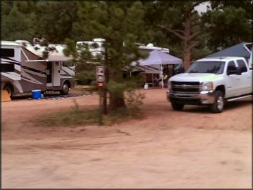 Close up photo of campsite with two RVs, an E-Z Up tent and a pickup truck.