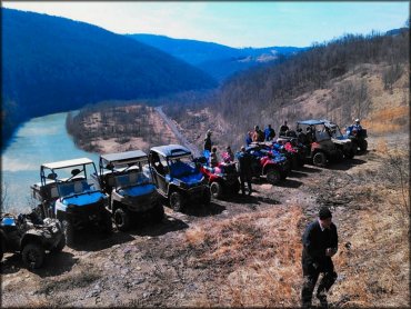 Scenic group photo of five UTVs and five ATVs parked in a line on top of a hill with the Potomac River in the background.