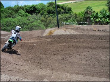 Young man on Kawasaki dirt bike going through berm on motocross track.