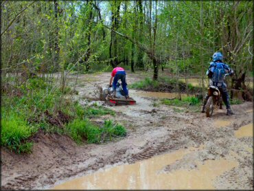 ATV and rider going through deep mud and water on the trail.