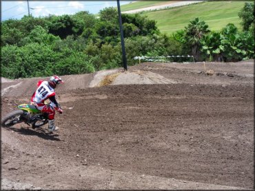 Man wearing Fly motocross gear riding Suzuki dirt bike on track.