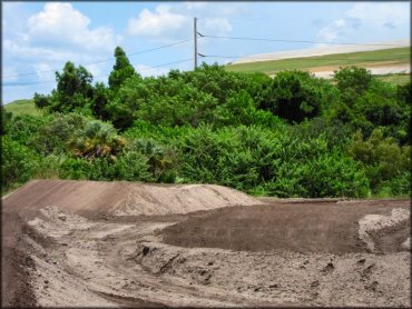 A scenic photo of motocross track surrounded by trees and bushes.