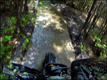 Dirt bike with GPS unit mounted on handlebar going through deep water crossing.