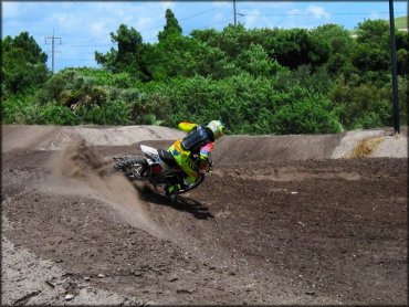 Man wearing Fox Racing motocross gear on dirt bike going through berm on track.