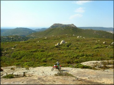 A scenic top down view of rider on Honda dirt bike with rolling hills in the background.