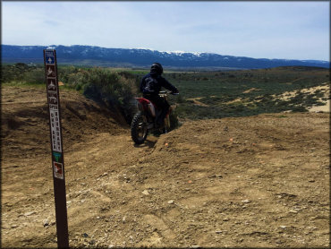 Rider on a Honda dirt bike begins descent down a steep trail.