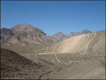 A far away photo of a steep and sandy hill climb.