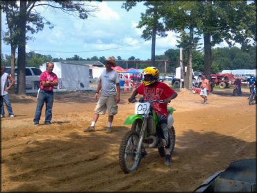 Kawasaki two-stoke with green plastic on dirt drag.