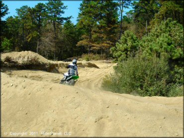 Kawasaki dirt bike going through sandy berm on motocross track.