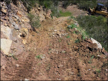 Mini bobcat dozer grading ATV trail.