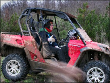 A Woman in a Red Can-Am Commander UTV on a Wooded Trail
