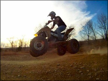Young man wearing motorcycle helmet, t-shirt and jeans riding an ATV.