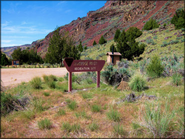 BLM sign for Jarbidge River Recreation Site with dirt parking lot, informational kiosk and vault toilet.