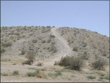 A view of hard packed ATV trail winding up small hill.